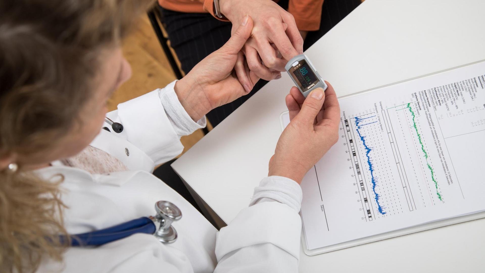 Eine Ärztin misst in einer Arztpraxis in Hamburg den Sauerstoffgehalt im Blut ihrer Patientin mit einem Pulsoximeter.
