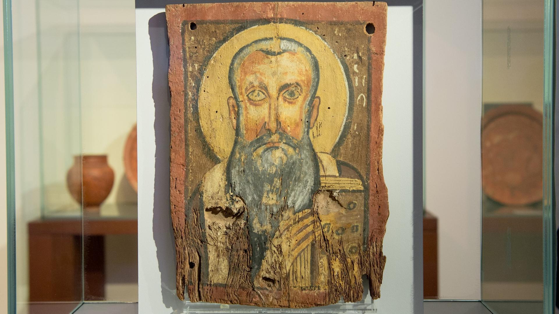 Die Ikone "Apa Abraham" in der Ausstellung "Ein Gott" im Berliner Bode-Museum. Ein gemaltes Bild eines Mannes mit grauem Bart auf rotem Stein, in einer Glasvitrine.