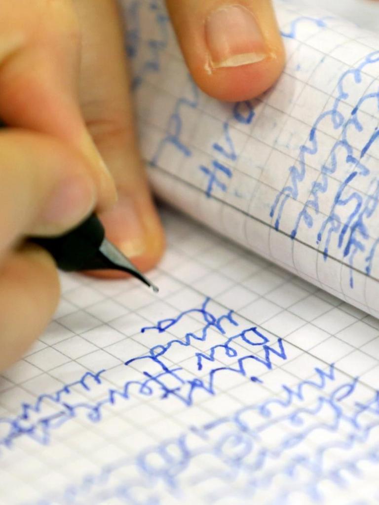 Eine Frau schreibt in der Volkshochschule Rostock bei einem Analphabeten-Grundkurs.