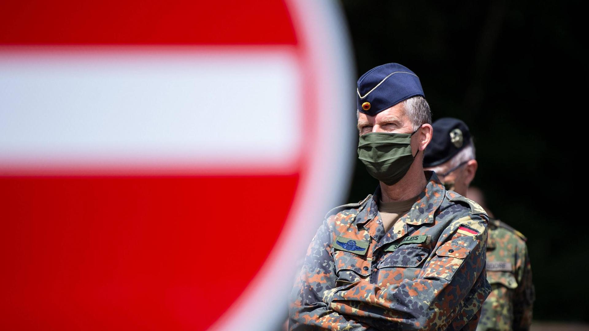 Ein Bundeswehroffizier mit Mund-Nasenschutz steht schräg hinter einem großen roten "Einfahrt verboten"-Schild.