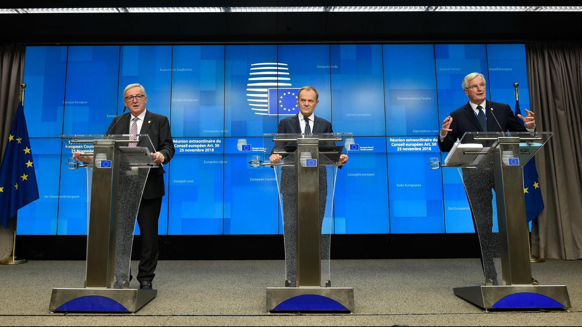 Juncker, Tusk und Michel Barnier (v.l.n.r.) stehen jeweils vor einem Redepult.