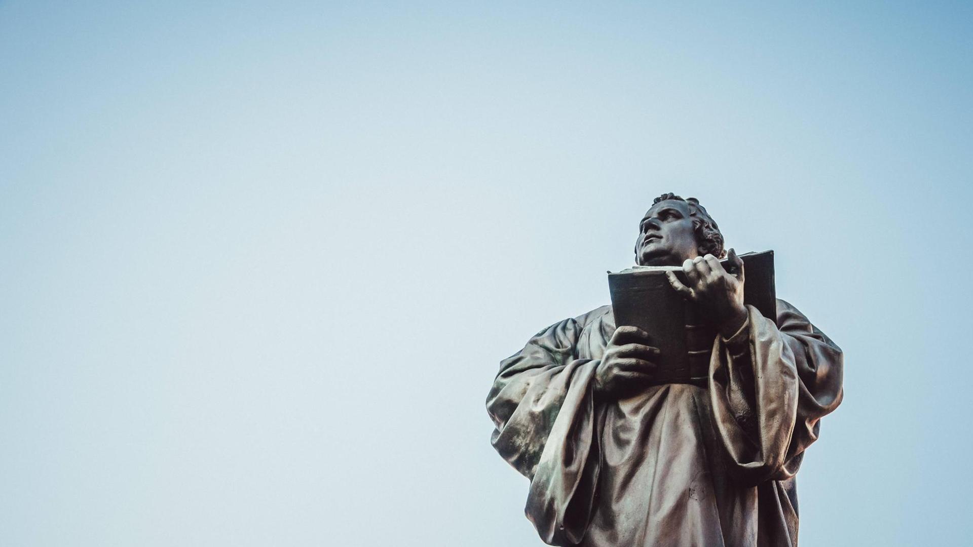 Das Luther-Denkmal in Erfurt von unten Richtung des leicht rosafarbenen Himmels fotografiert.