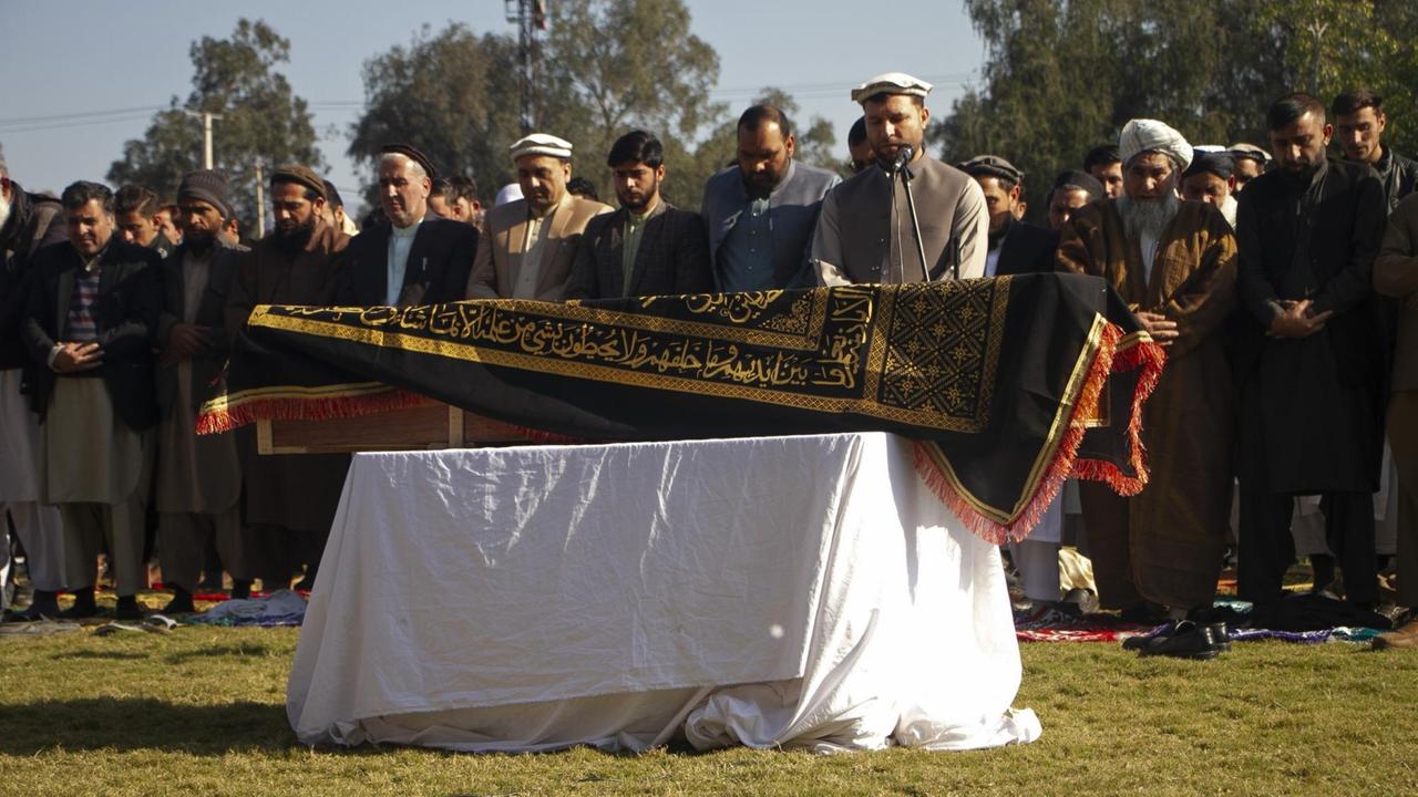 Mehrere Männer stehen am 10.12.2020 in Kabul vor dem Sarg der afghanischen TV-Moderatorin Malala Maiwand und beten.
