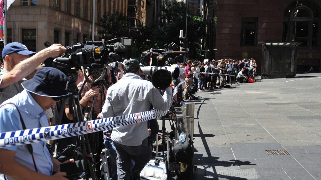 Medienvertreter und Schaulustige versammeln sich nahe des Cafés in Sydney, in dem ein Mann mutmaßlich bis zu 30 Geiseln genommen hat.