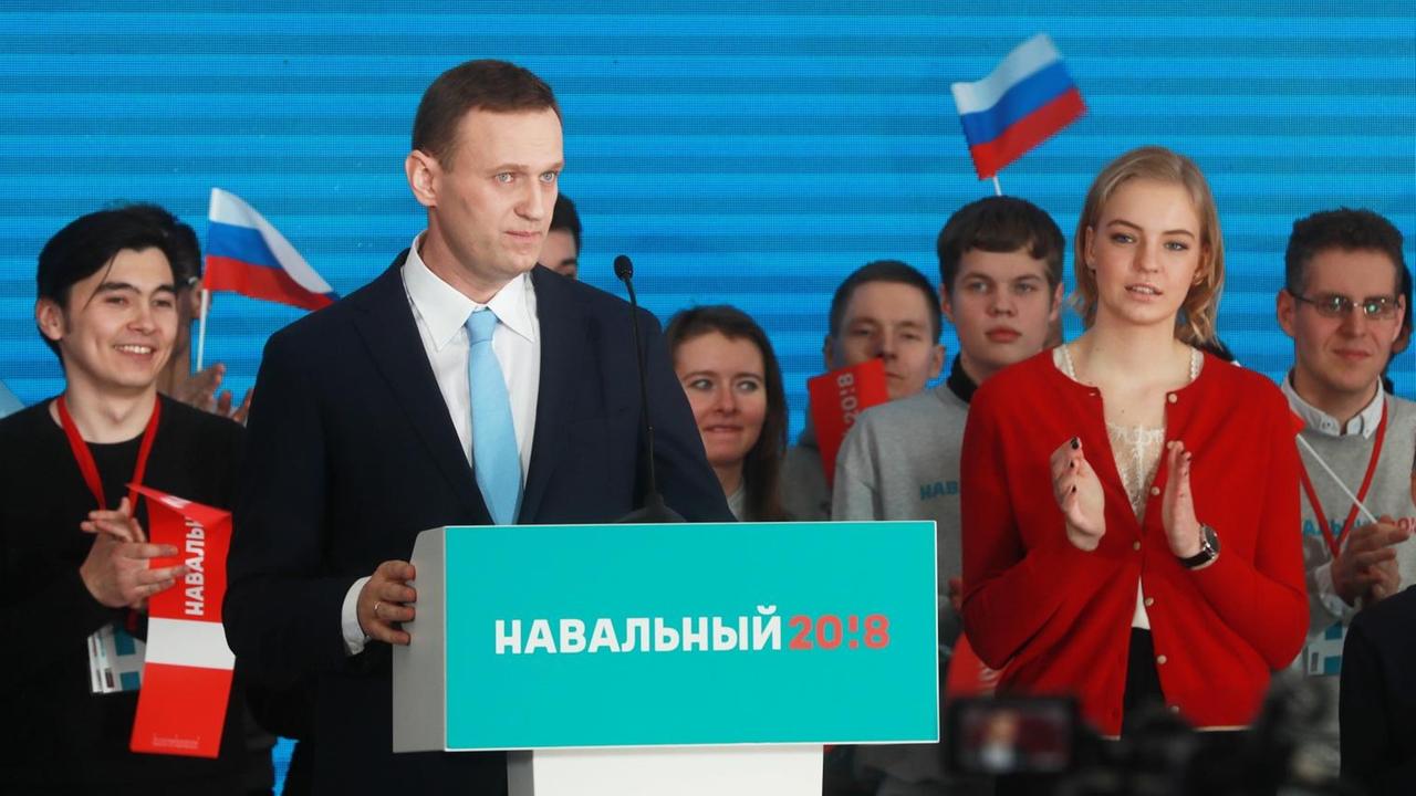 Nawalny auf der Bühne, hinter ihm Unterstützer, die ihm applaudieren.