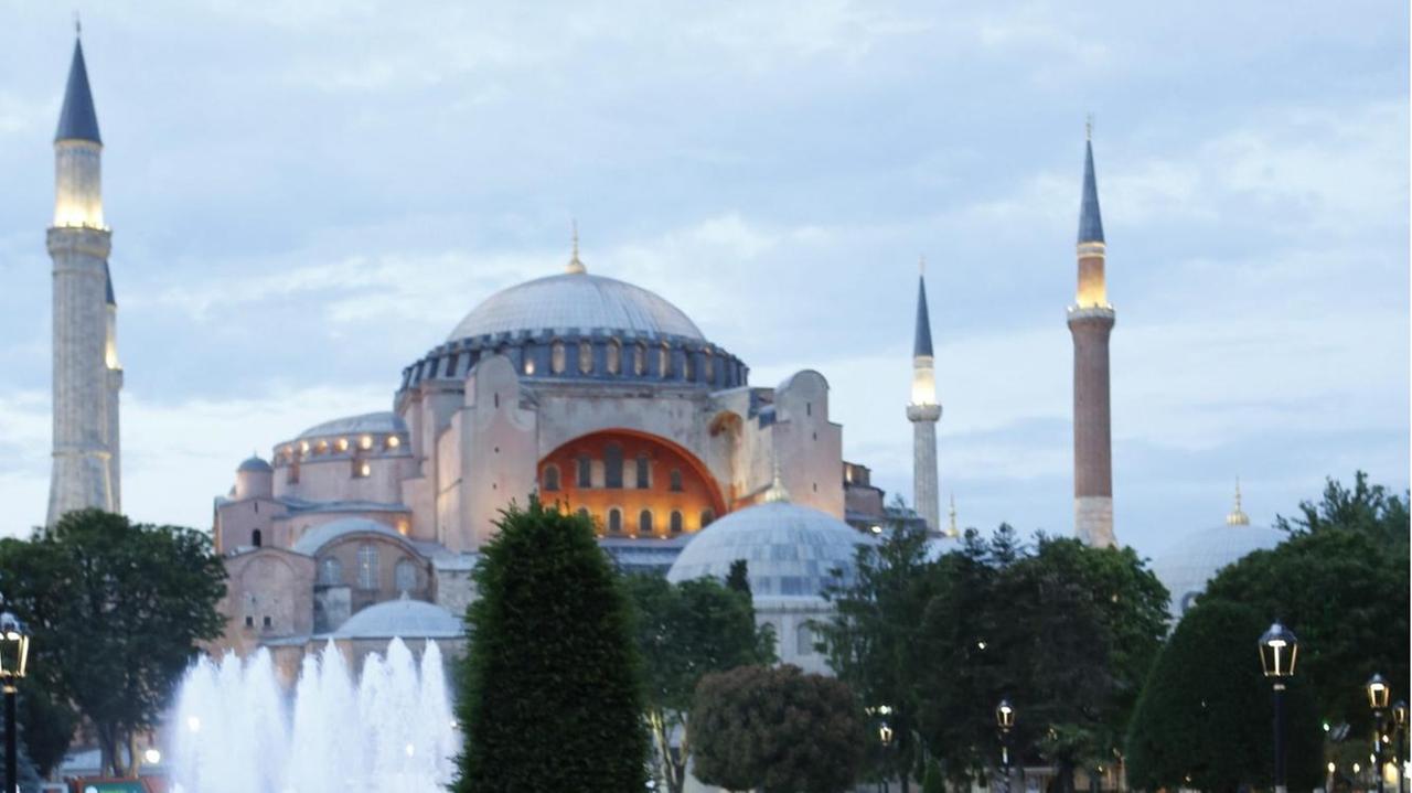 Muslime warten auf einer Grünfläche vor der Hagia Sophia in Istanbul darauf am ersten Tag des Fastenmonats Ramadan wieder etwas zu essen.