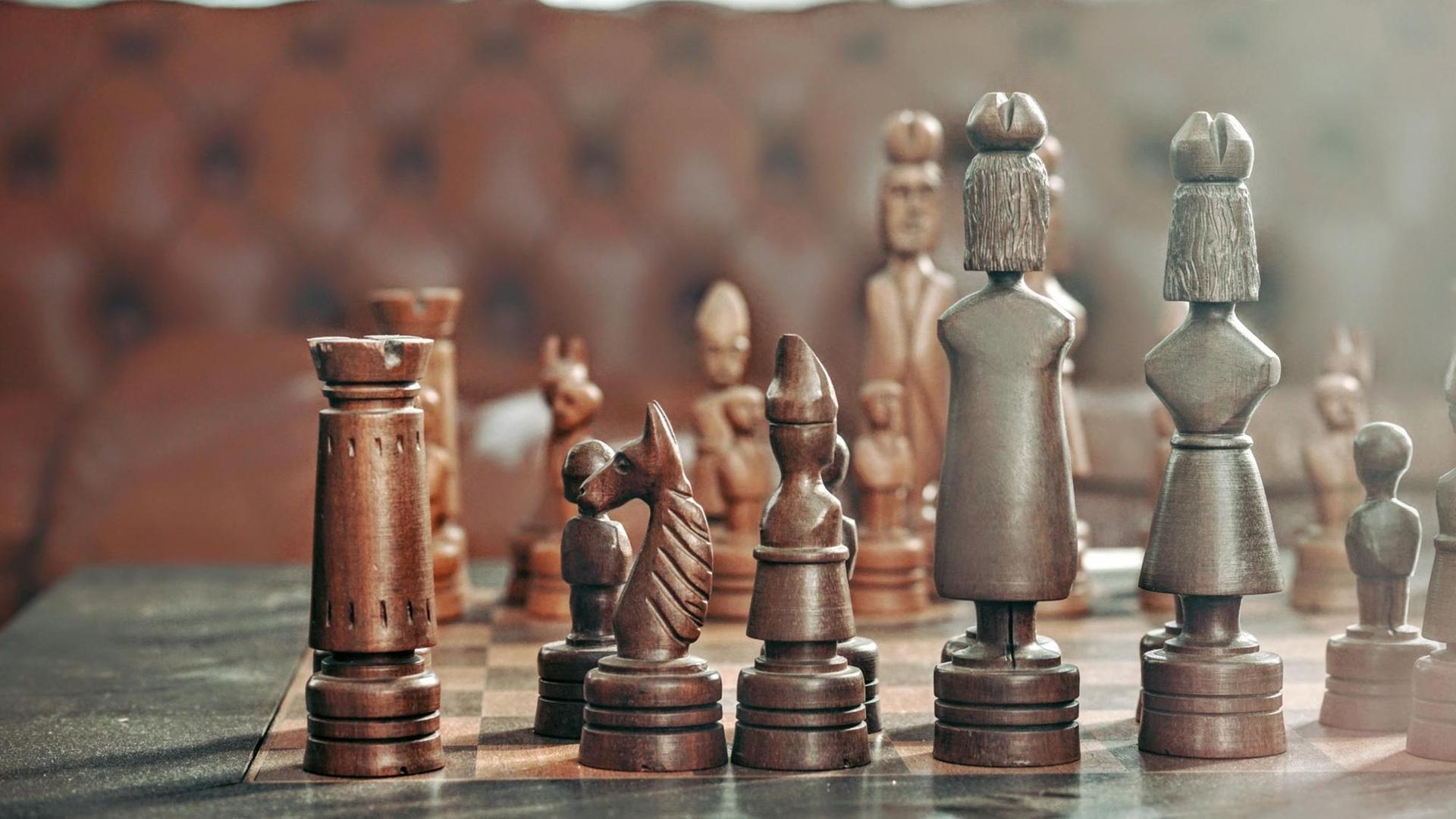 Schachfiguren aus Holz auf einem Schachbrett.