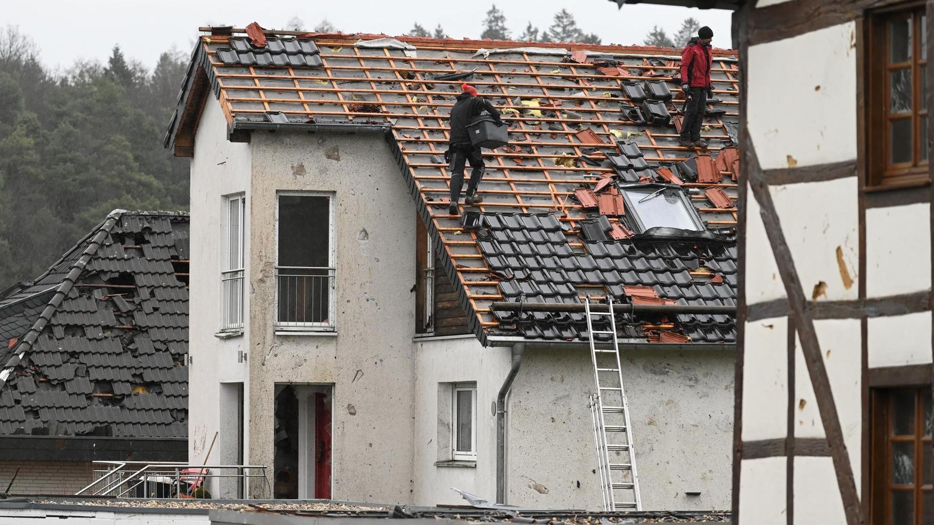 14.03.2019, Nordrhein-Westfalen, Roetgen: Dachdecker arbeiten an einem Haus, dessen Dach durch einen Tornado beschädigt wurde. In der Eifel-Gemeinde Roetgen südlich von Aachen geht das Aufräumen und die Reparatur der beschädigten Häuser los.