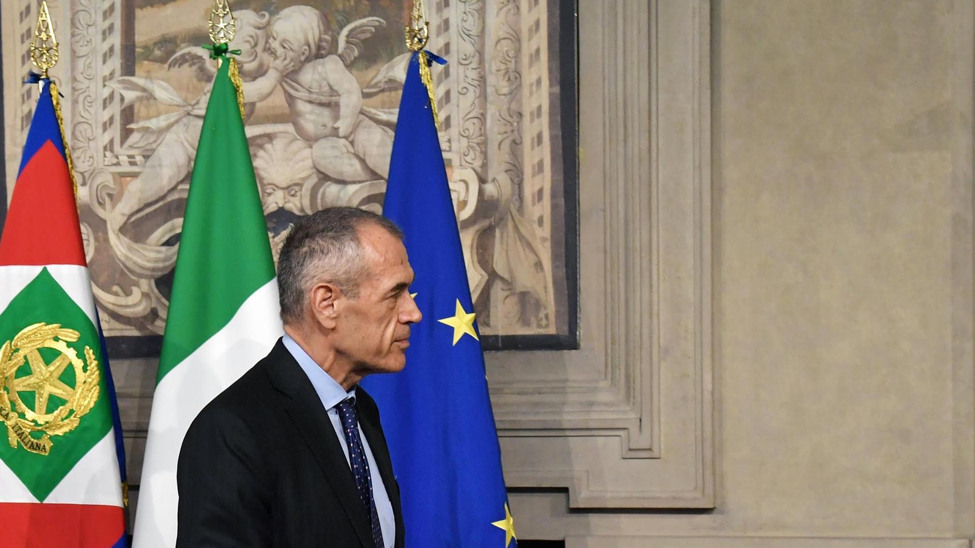Carlo Cottarelli vor einer italienischen und einer europäischen Flagge