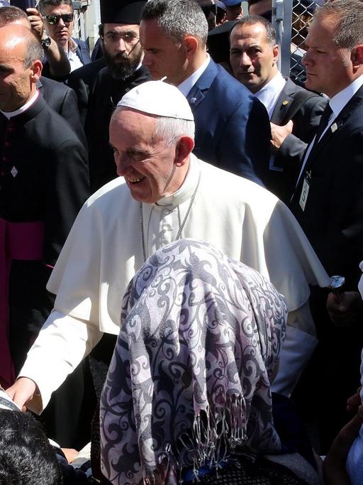 Papst Franziskus wird beim Besuch des Flüchtlingslagers Moria auf der griechischen Insel Lesbos von Flüchtlingskindern besucht. Er wird begleitert von Bartolomaios, dem orthodoxen Patriarchen von Konstantinopel.