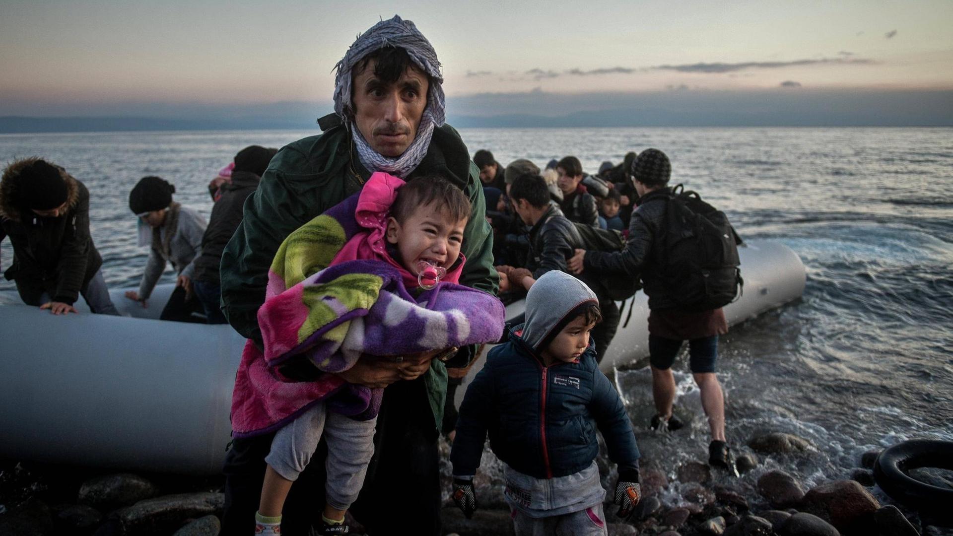 Lesbos, Skala Sikaminias: Ein afghanischer Vater trägt sein Kind, nachdem die beiden und weitere Flüchtlinge mit einem Schlauchboot an Land gegangen sind
