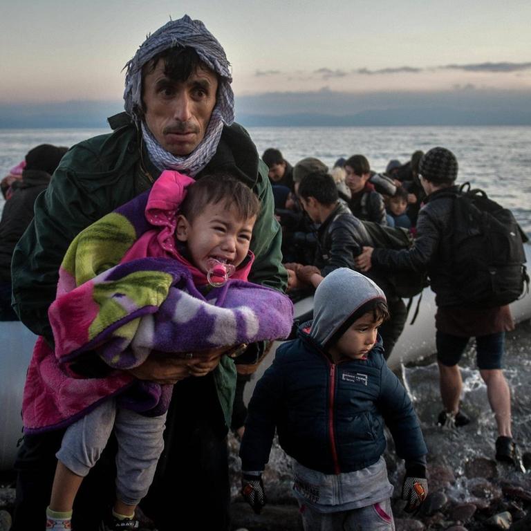 Lesbos, Skala Sikaminias: Ein afghanischer Vater trägt sein Kind, nachdem die beiden und weitere Flüchtlinge mit einem Schlauchboot an Land gegangen sind