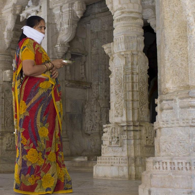 Eine Anhängerin des Jainismus mit einer traditionellen Maske in einem indischen Tempel