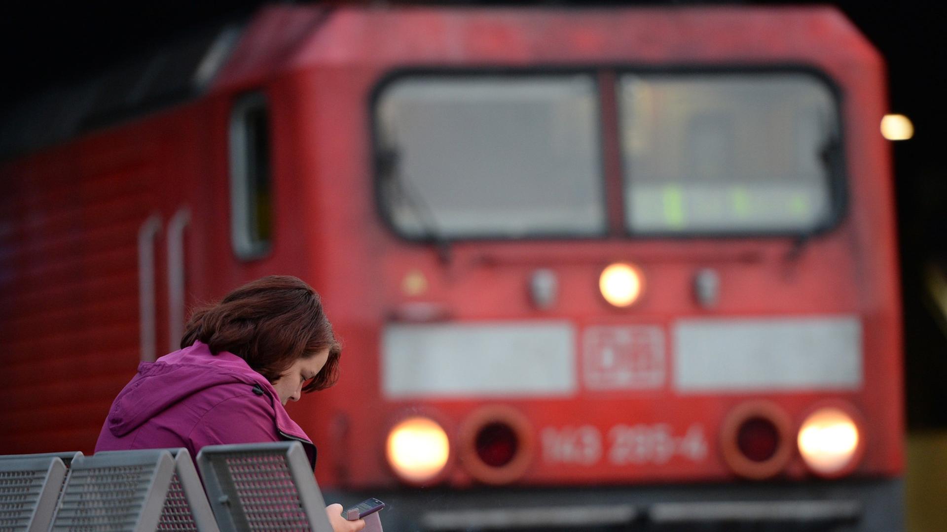 Eine Frau sitzt am 06.09.2014 im Hauptbahnhof in Hamburg vor einem Triebwagen der Bahn.