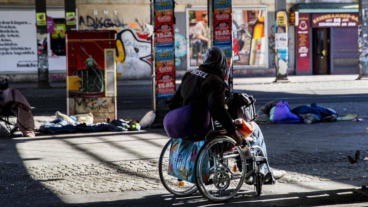 Ein einsamer Obdachloser auf dem Rollstuhl am Alexanderplatz in Berlin.