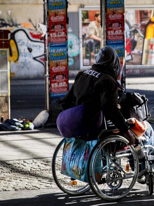 Ein einsamer Obdachloser auf dem Rollstuhl am Alexanderplatz in Berlin.