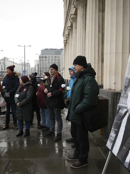 Ein Dutzend Demonstranten stehen in einer Grupper zusammen vor dem Sitz des Staatssenders TVP. Im Vordergrund ist ein groß ausgedrucktes Bild des ermordeten Danziger Bürgermeister Pawel Adamowicz zu sehen.