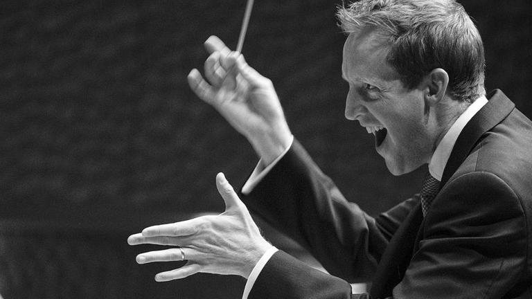 Der Dirigent Justin Doyle dirigiert ein Orchester