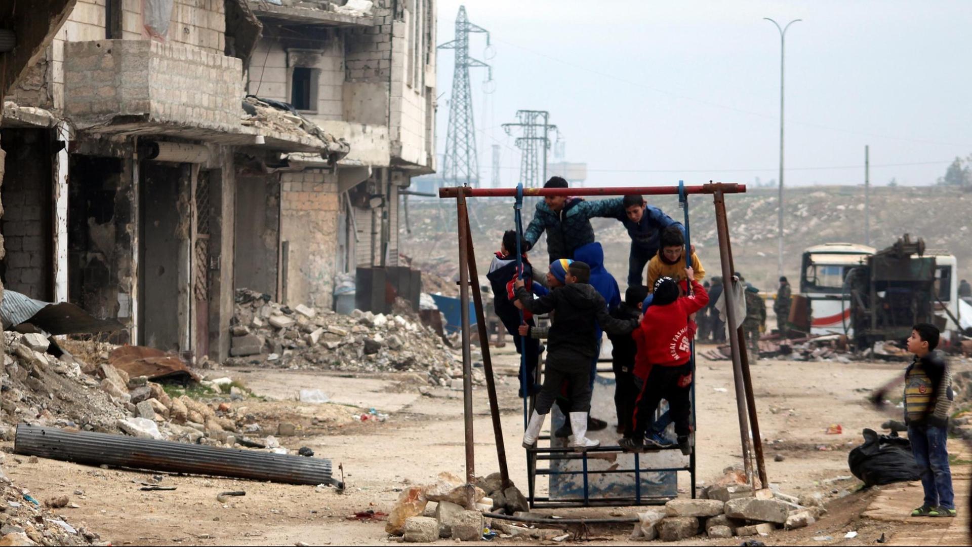 Kinder spielen in Aleppo vor zerstörten Gebäuden
