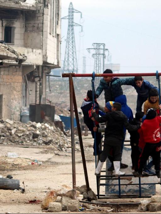 Kinder spielen in Aleppo vor zerstörten Gebäuden