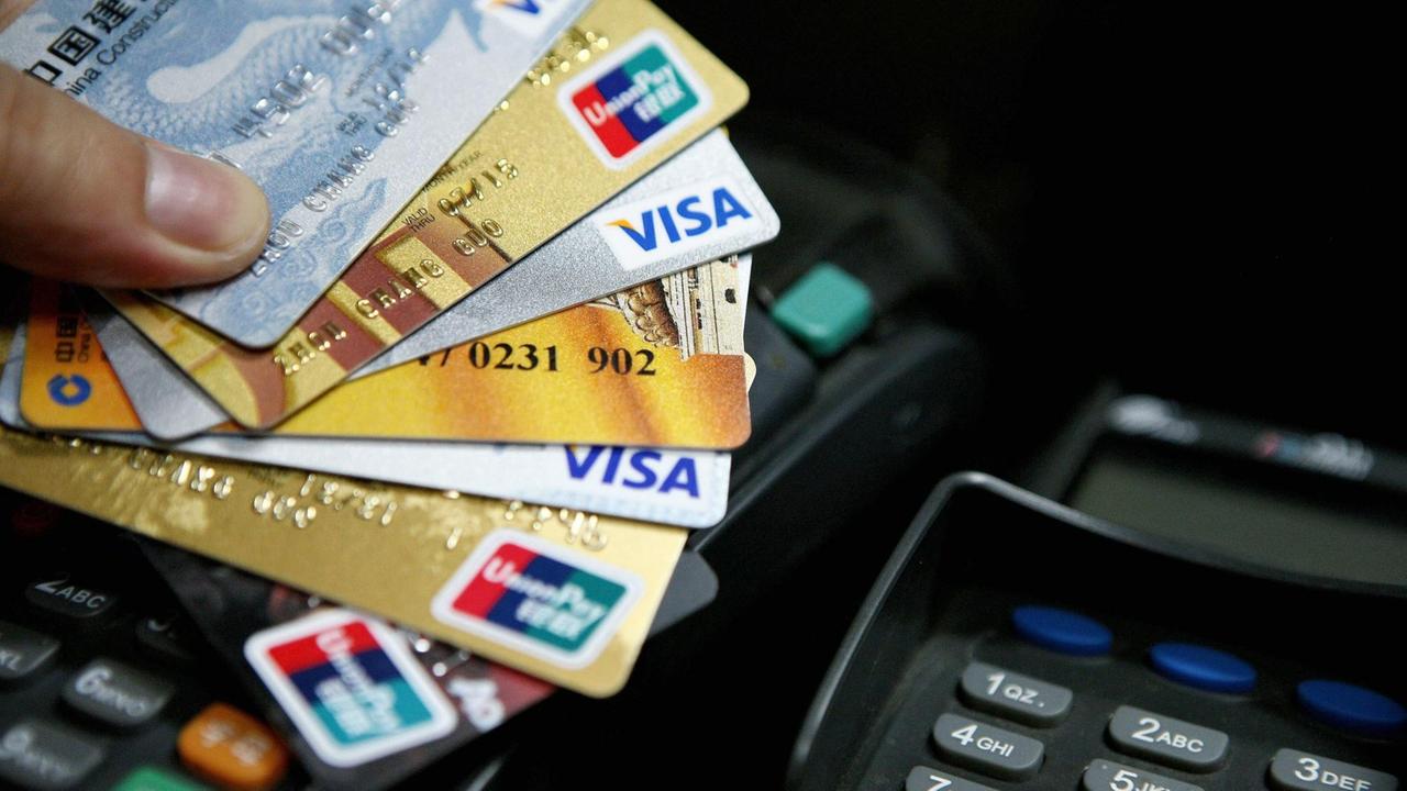 Ein Mann hält eine Reihe von Kreditkarten aufgefächert in seiner Hand.