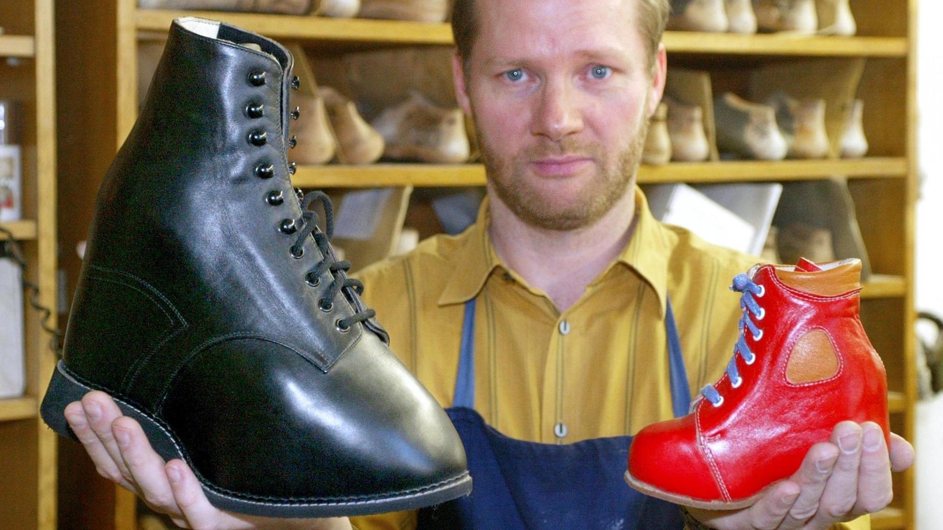 Ein orthopädischer Schuhmachermeister hält am 17.01.2003 zwei seiner gefertigten Schuhen in den Händen.