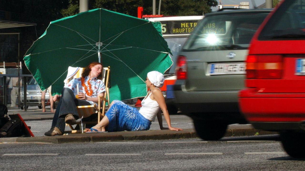 Zwei Aktivistinnen von Robin Wood haben es sich am 22.9.2003 mitten im dichten Autogetümmel auf einer Verkehrsinsel vor dem Hamburger Dammtor-Bahnhof gemütlich gemacht.