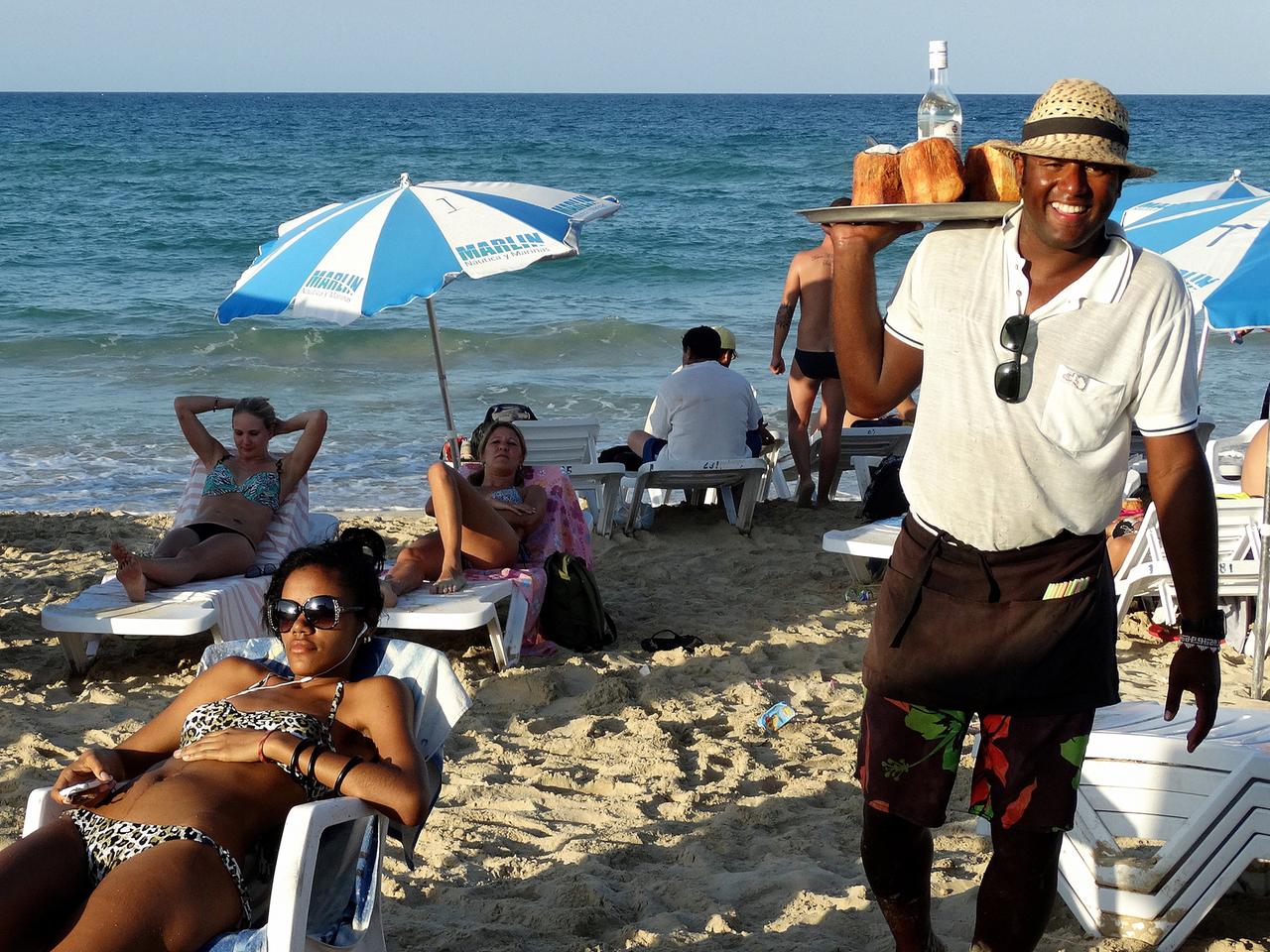 Manuel balanciert gekonnt das Tablett mit den Kokosnüssen und der Rumflasche über den Strand von Santa Maria del Mar.