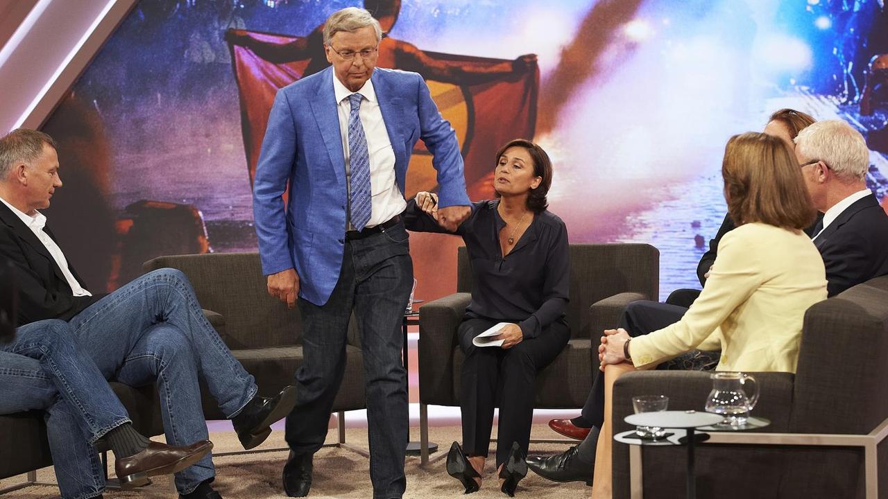 Bosbach ist gerade aufgestanden und geht. Er schüttelt die Hand Maischbergers ab, die ihn zum Bleiben bewegen wollte. Die anderen Talkgäste schauen zu.