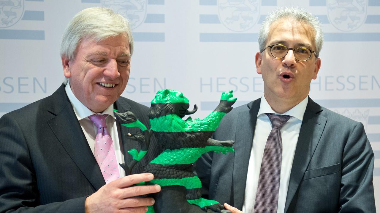 Der hessische Ministerpräsident Volker Bouffier (CDU) und sein Stellvertreter Tarek Al-Wazir (Die Grünen) hantieren mit einem schwarz-grünen "Hessenlöwen"