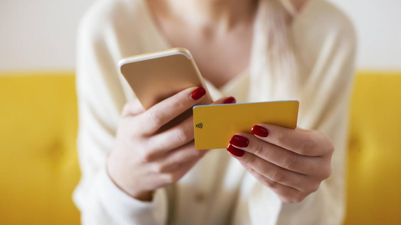 Blonde woman using smartphone and using bank card at home model released Symbolfoto property released PUBLICATIONxINxGERxSUIxAUTxHUNxONLY EBSF02398