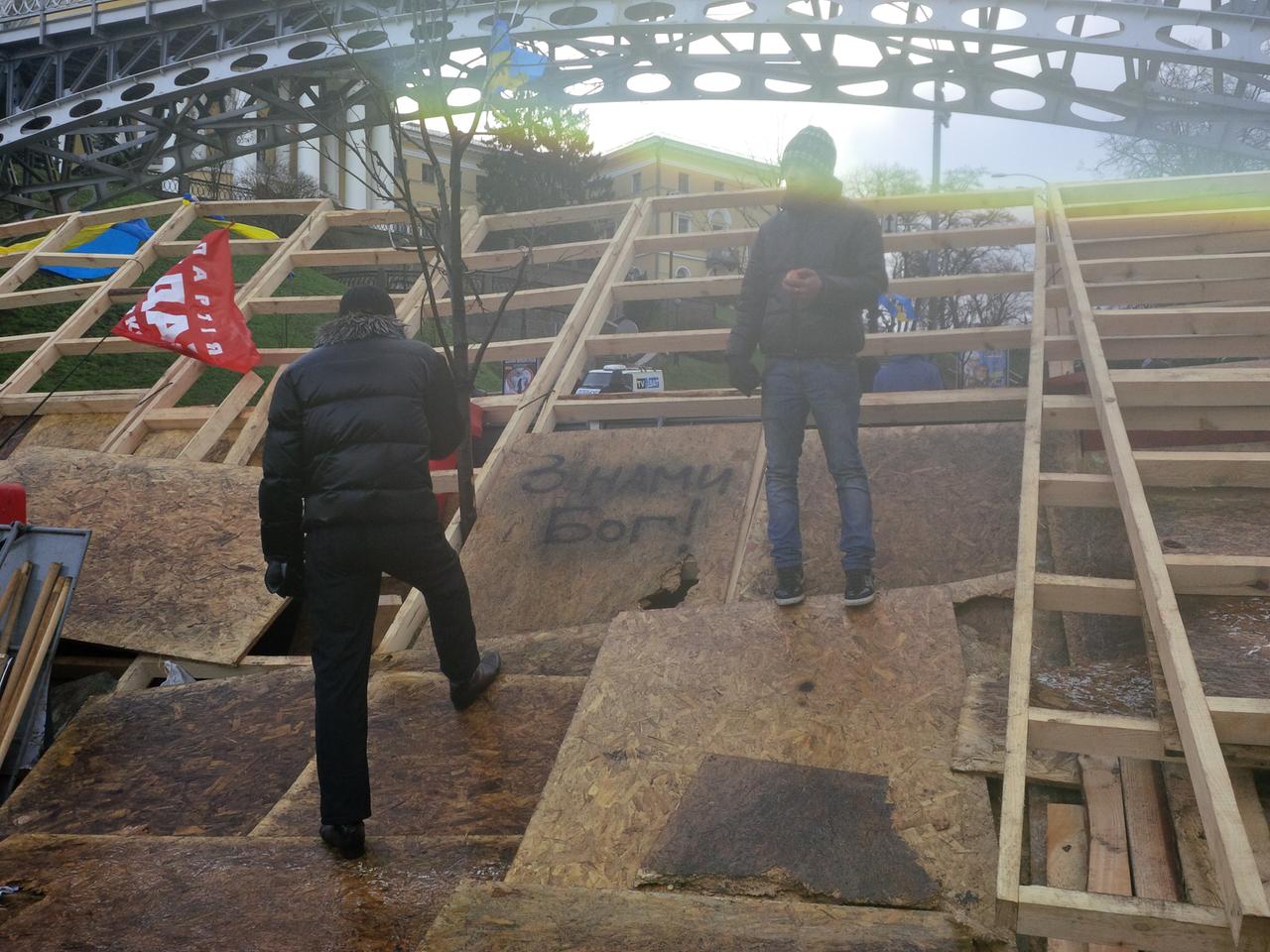 Zwei Oppositionelle stehen auf einer aus Brettern errichteten Straßensperre vor einer Brücke im Regierungsviertel in Kiew.