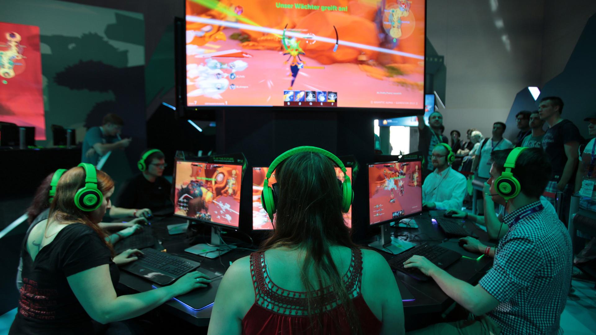 Besucher der Gamescom testen in Köln das Computer Spiel Gigantic.