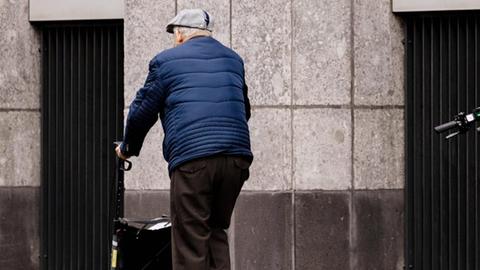 Rentner mit Rollator passiert E-Scooter der Firma Lime in der Kölner Innenstadt.