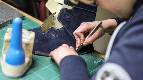 Eine Auszubildende zur Orthopaedieschuhmacherin schneidet am 29.01.2020 in Stuttgart das Leder eines orthopaedischen Schuhs zurecht. Foto: Christoph Schmidt