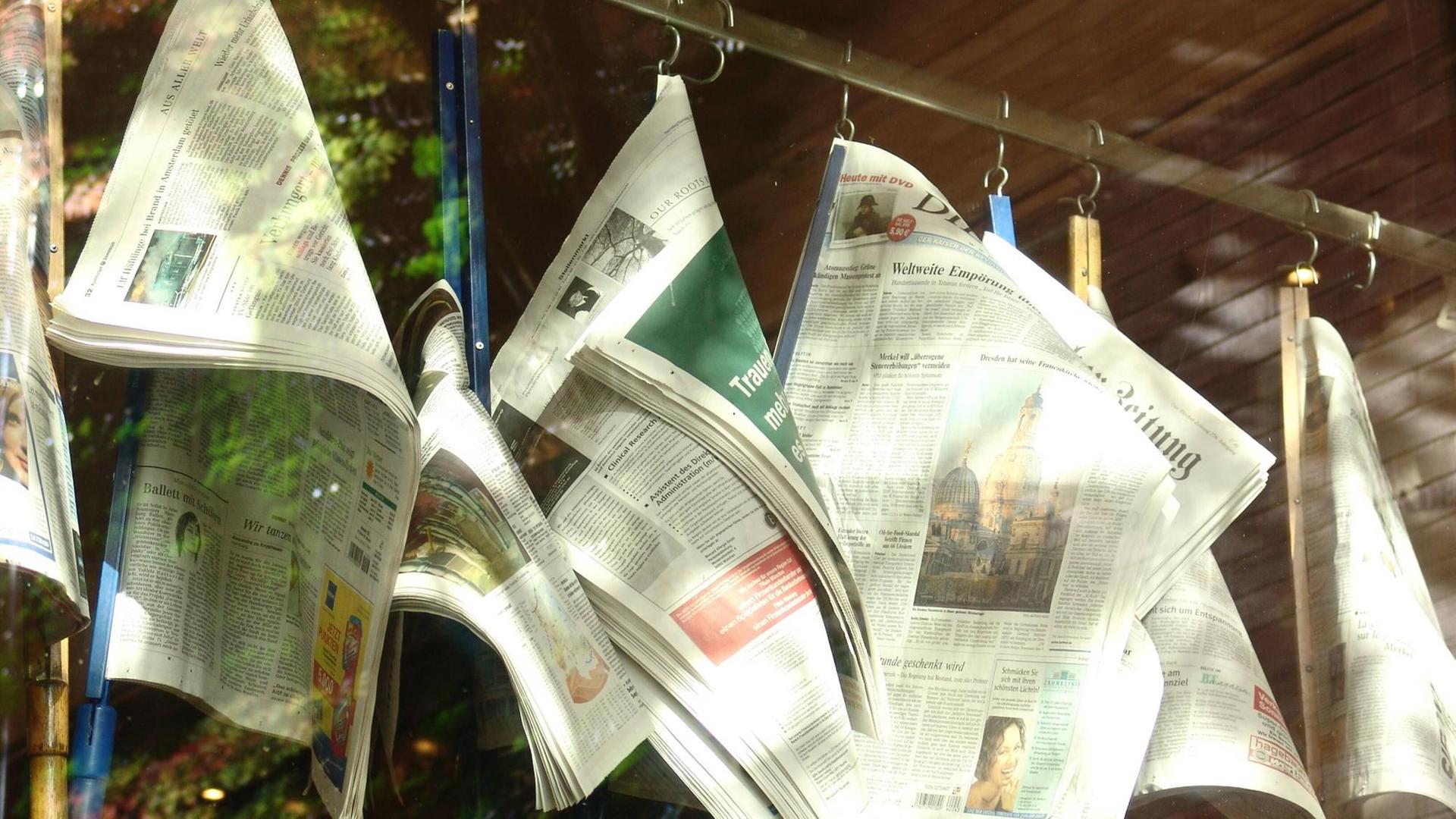 Zeitungen hängen an einem Ständer in einem Kaffeehaus.