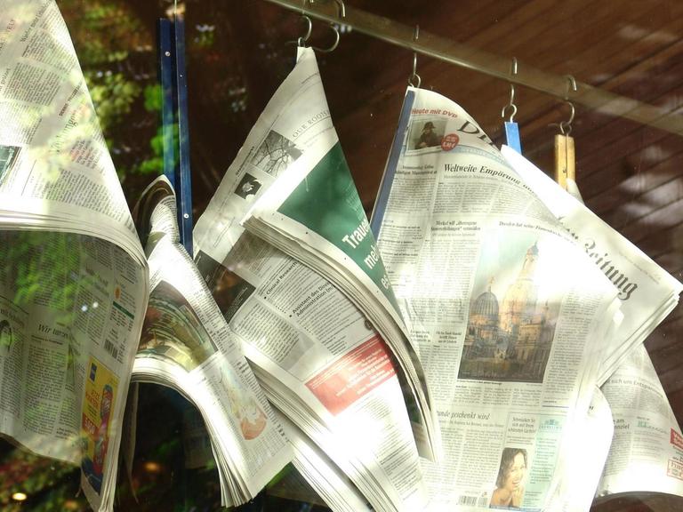Zeitungen hängen an einem Ständer in einem Kaffeehaus.