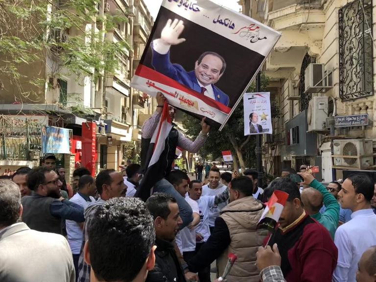 Demontranten während der Präsidentschaftswahl in Ägypten. Vor einem Wahllokal halten sie ein Bild von Präsident al-Sisi in die Höhe.