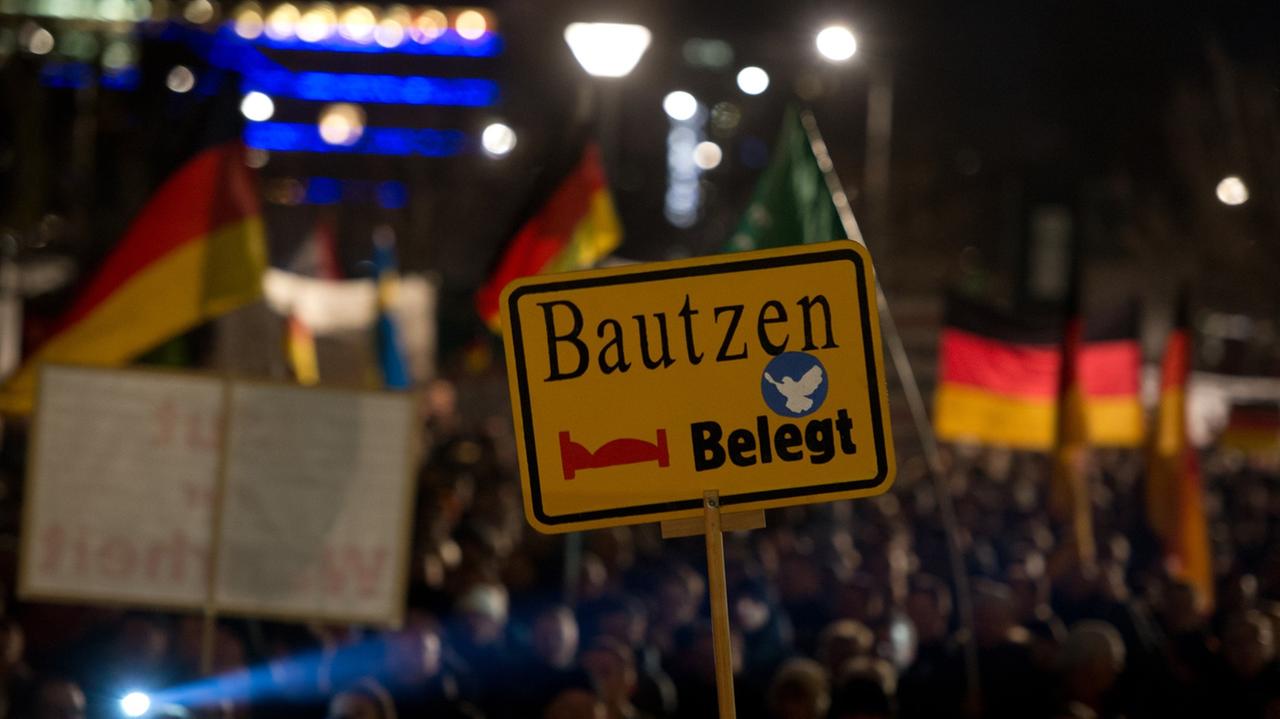Teilnehmer der Kundgebung der Pegida in Dresden halten am 15.12.2014 bei der Kundgebung in Dresden ein Schild mit der Aufschrift "Bautzen belegt" hoch.