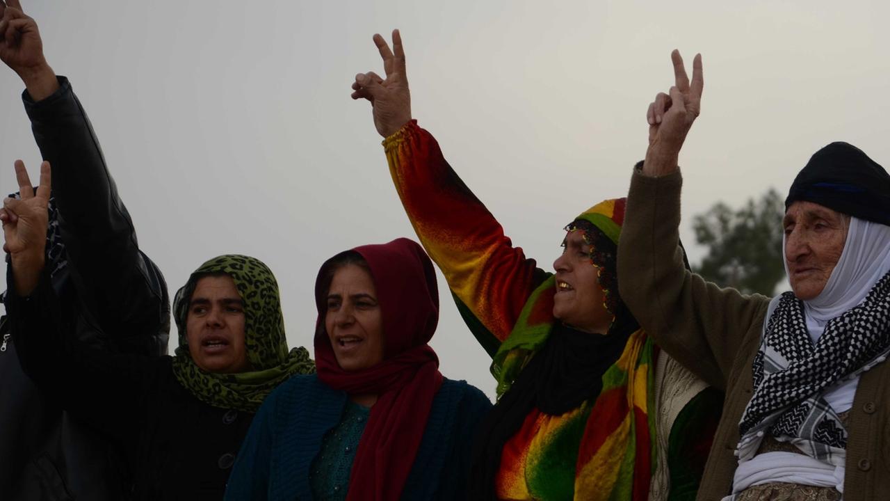 Aktivisten verlesen Neues von der Front in Kobane und die Menschen rufen Durchhalteparolen