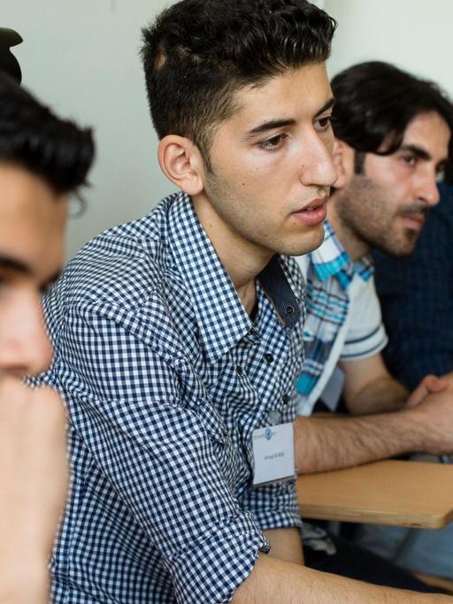 Mehrere junge Männer sitzen in einem Unterrichtsraum in einer Reihe nebeneinander
