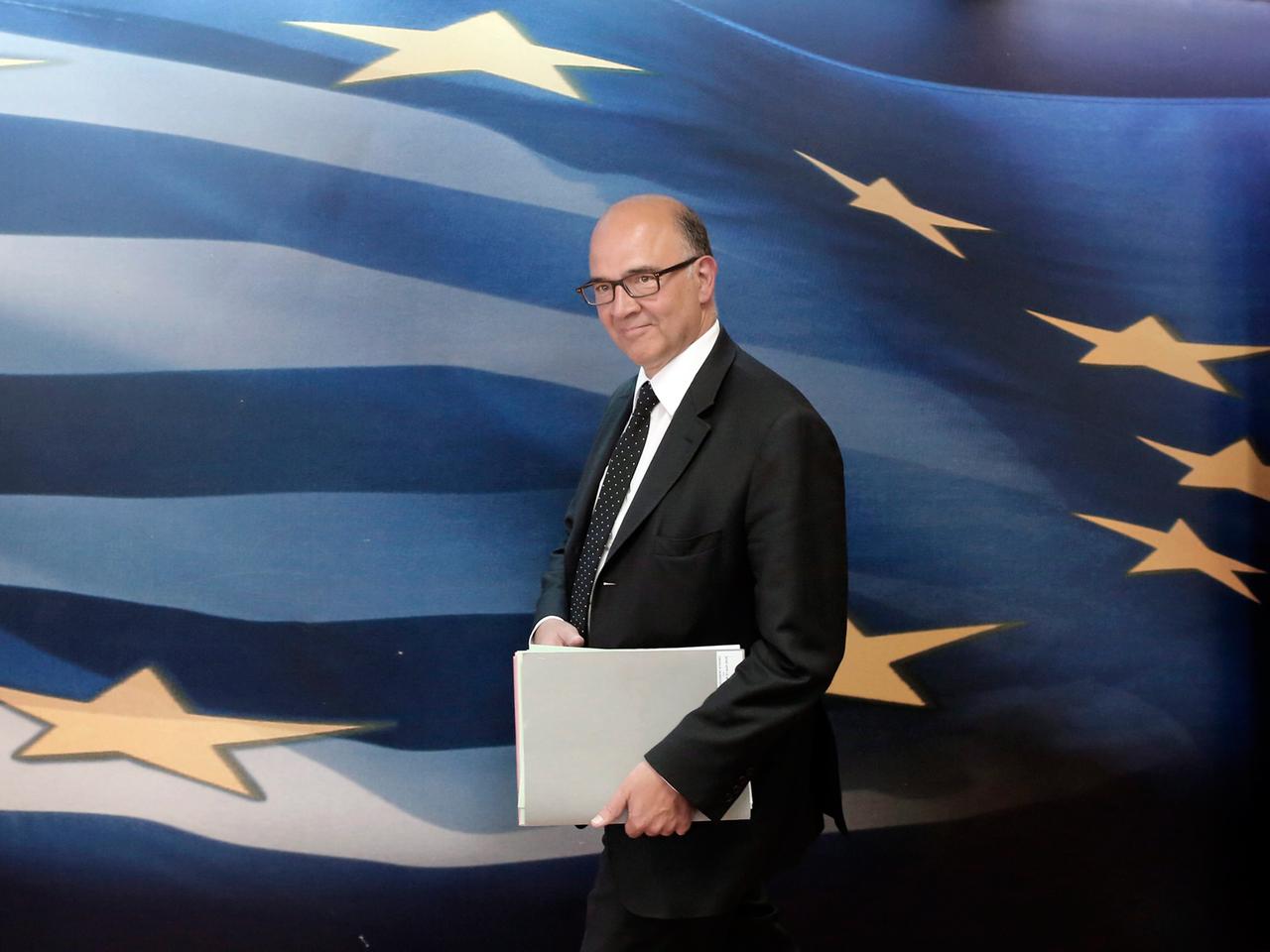 Frankreichs ehemaliger Finanzminister und Kandidat für die EU-Kommission Pierre Moscovici, geht vor einer großen blauen EU-Flagge mit gelben Sternen und weißen Streifen entlang