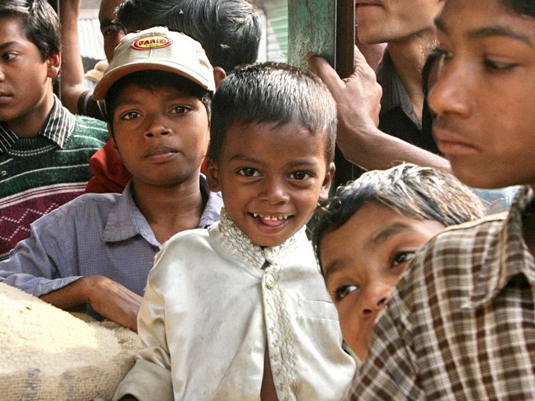 Kinder stehen in Bangladesch vor einem Marktstand, wo es günstigen Reis gibt.