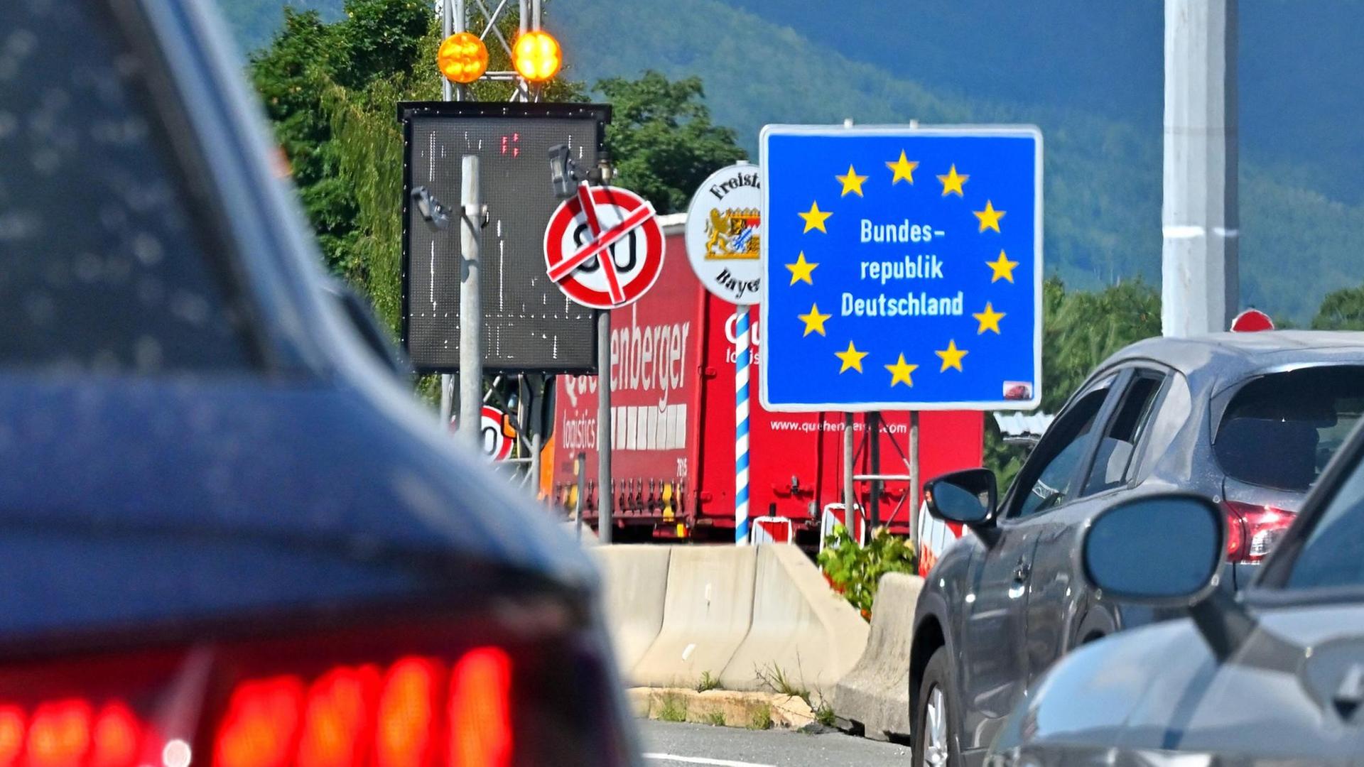 Mehrere PKW stehen im Stau. Grenzschilder an der Autobahn am Walserberg bei der Einreise von Österreich nach Deutschland