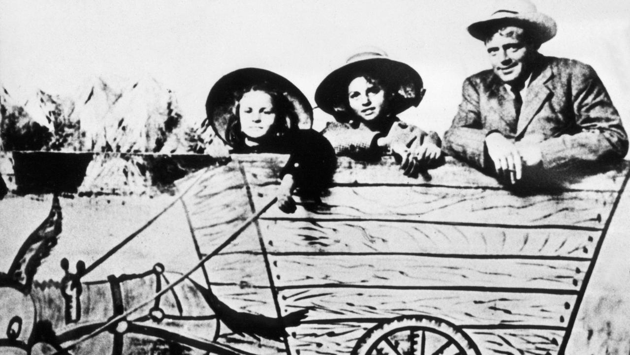 Der amerikanische Schriftsteller Jack London mit seinen beiden Töchtern Becky (l) und Joan auf einem Spaßbild mit einem gemalten Eselskarren (undatiert).