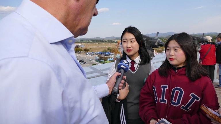 2 südkoreanische Schülerinnen sprechen in das Mikrofon des Reporters.
