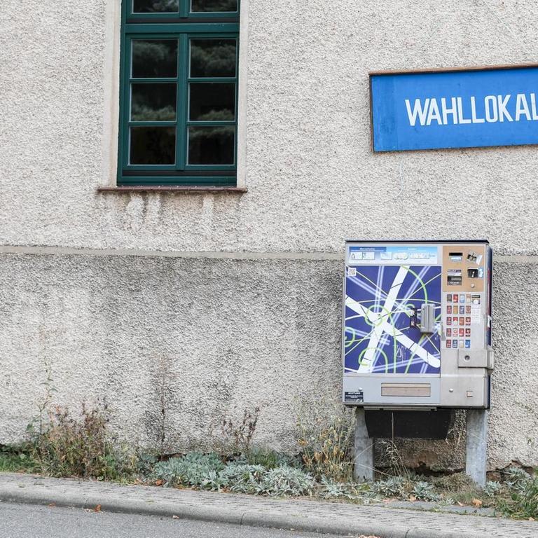 In dem sächsischen Ort Cannewitz hängt an einer Hauswand ein blaues Schild mit der weißen Aufschrift "Wahllokal". Darunter ist ein Zigarettenautomat.