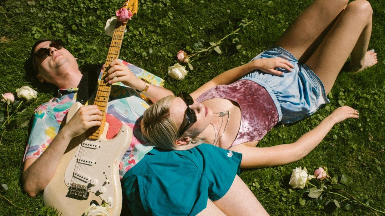Julia Leimenstoll und Martin Sladek mit Gitarre liegen im Gras