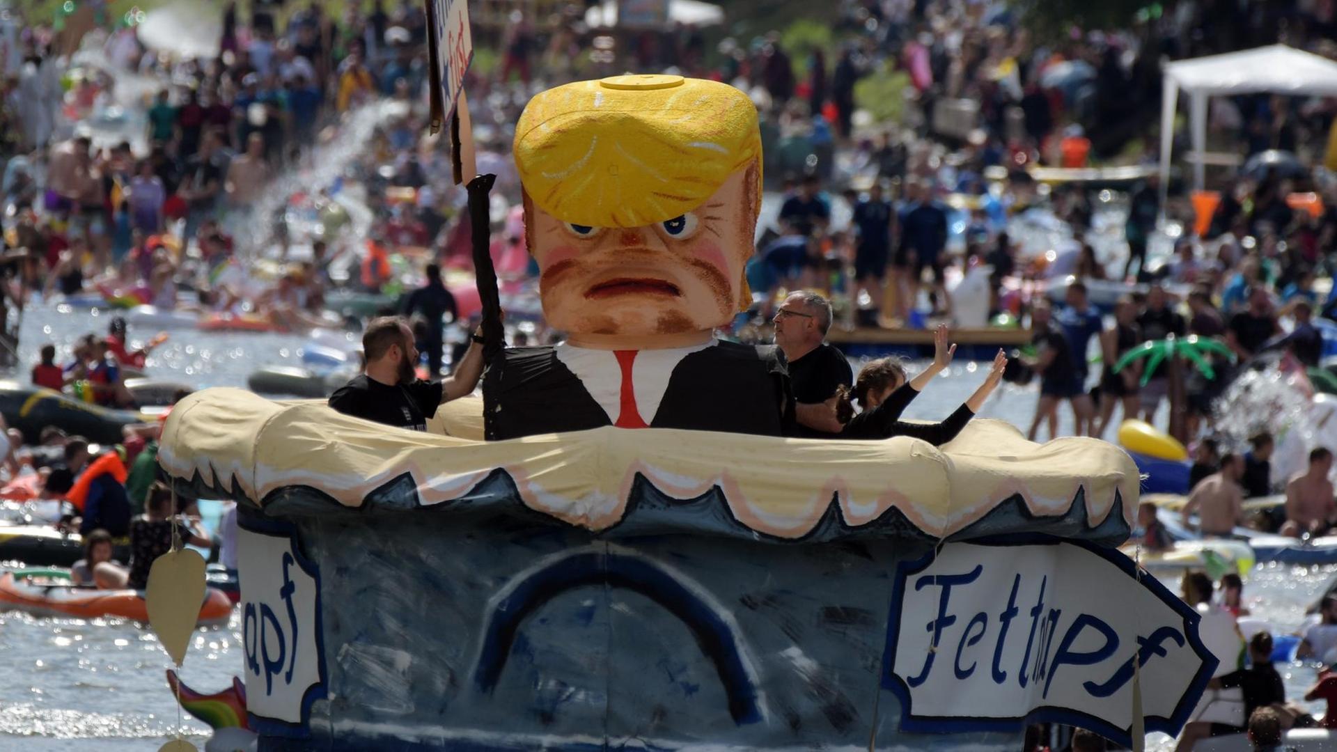Das Foto zeigt ein Themenboot, das US-Präsident Donald Trump in einem überdimensionalen Fettnapf zeigt.