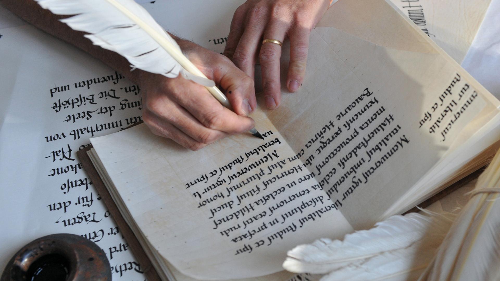 Eine Hand schreibt mit einer Schreibfeder in altertümlicher Schrift in ein Heft. 